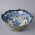 Close view inside a Ko-Imari kintsugi bowl, cobalt lotus and reed painting crossed by fine 24K gold seams converging toward the center, restored with natural urushi in Japan.
