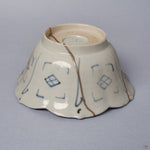 Side profile of a Ko-Imari kintsugi bowl, foliate rim and blue diamond-lattice exterior joined by a long pure silver seam, restored with natural urushi in Japan.