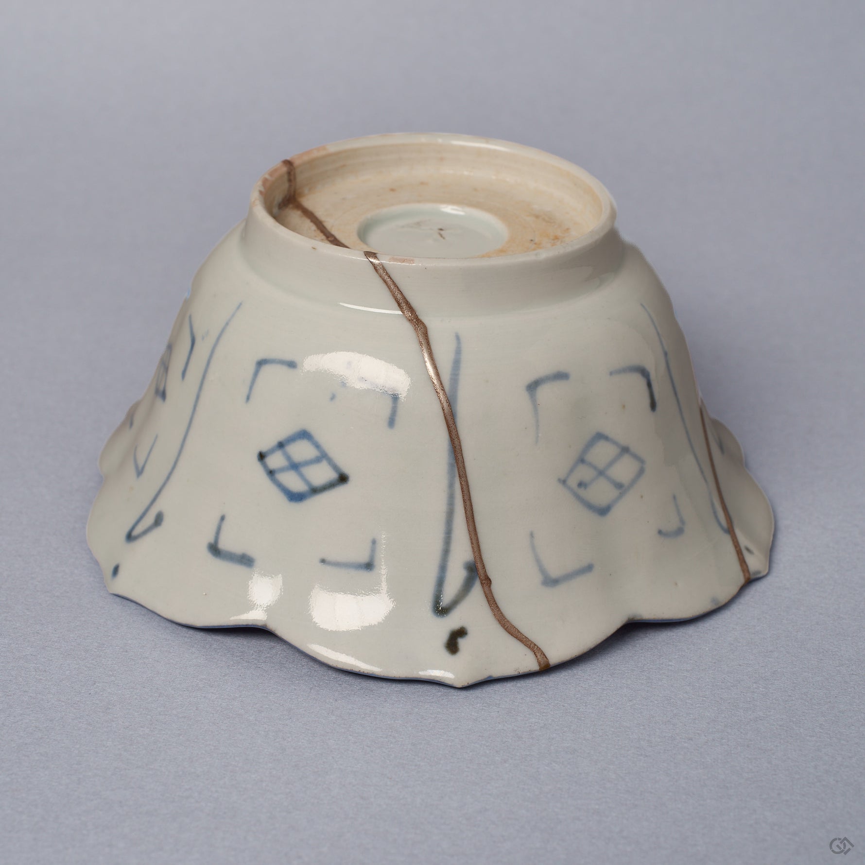 Side profile of a Ko-Imari kintsugi bowl, foliate rim and blue diamond-lattice exterior joined by a long pure silver seam, restored with natural urushi in Japan.