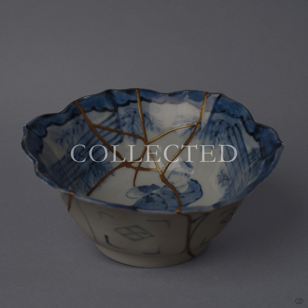 Ko-Imari blue-and-white porcelain bowl with a cobalt sage-and-bamboo interior, foliate rim, 24K gold kintsugi seams within and pure silver seams outside, restored with natural urushi. Sold out.