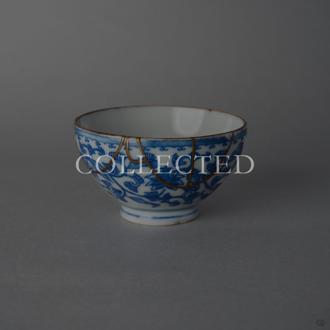 Edo-period Ko-Imari sake cup with hand-painted karakusa vines in sometsuke blue, restored with draped 24K gold kintsugi arcs in natural urushi. Collected.
