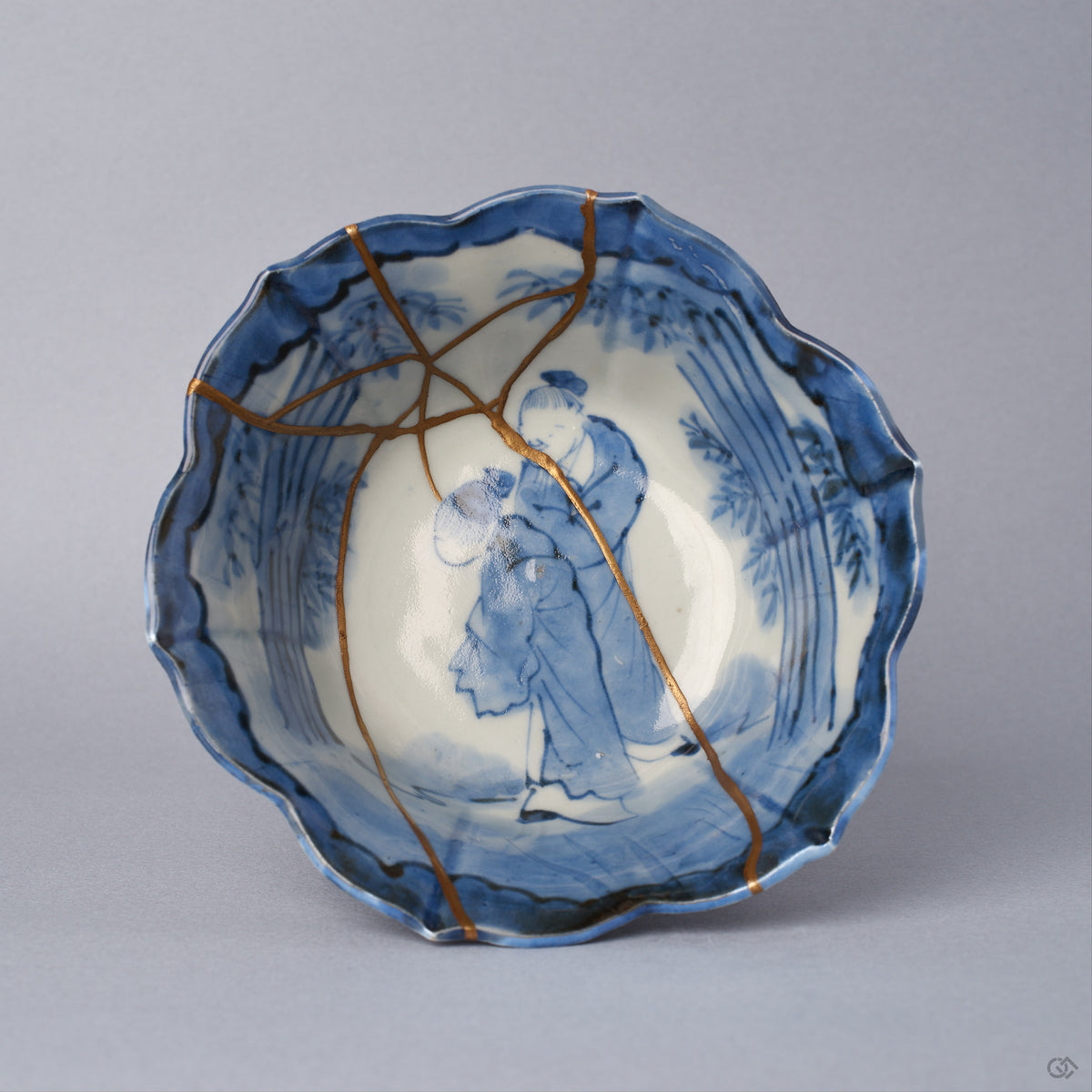 Top view into a Ko-Imari kintsugi bowl, two cobalt figures — a sage and attendant among bamboo — framed by 24K gold seams converging at the center, restored with natural urushi.