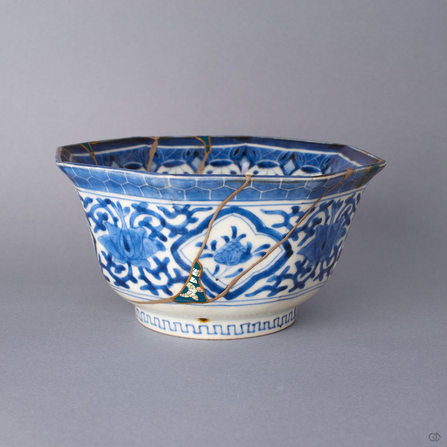 Front view of an octagonal Ko-Imari bowl in sometsuke blue, a lower-body loss filled with green urushi and raden and edged in 24K gold, with pure silver seams tracing the karakusa vine.