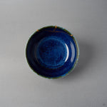Kintsugi bowl seen from above; the urushi and 24K gold seam crosses the olive-green rim and branches onto the starry night-blue interior.
