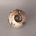 Bottom view of a kintsugi Shigaraki earthenware cup showing the unglazed foot ring and base, silver restoration lines visible where fragments meet the underside.