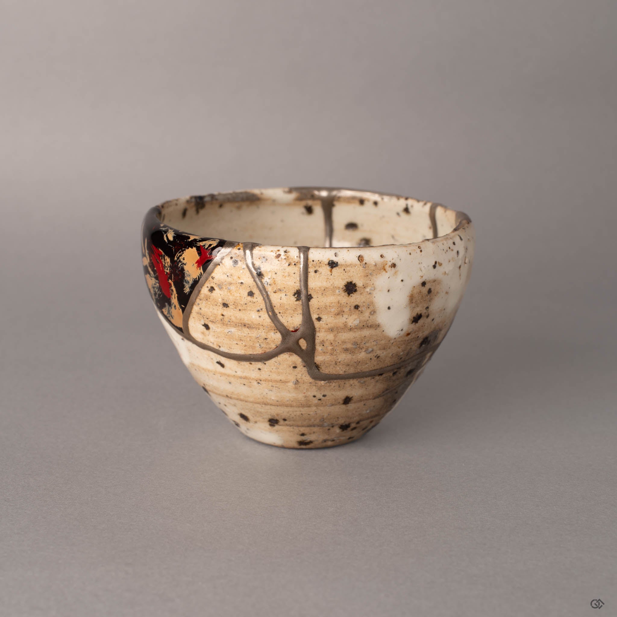Side view of a kintsugi Shigaraki cup showing silver seams crossing the earthy ivory surface, hand-thrown texture visible in the clay body, a tactile history shaped by potter and lacquer artist alike.