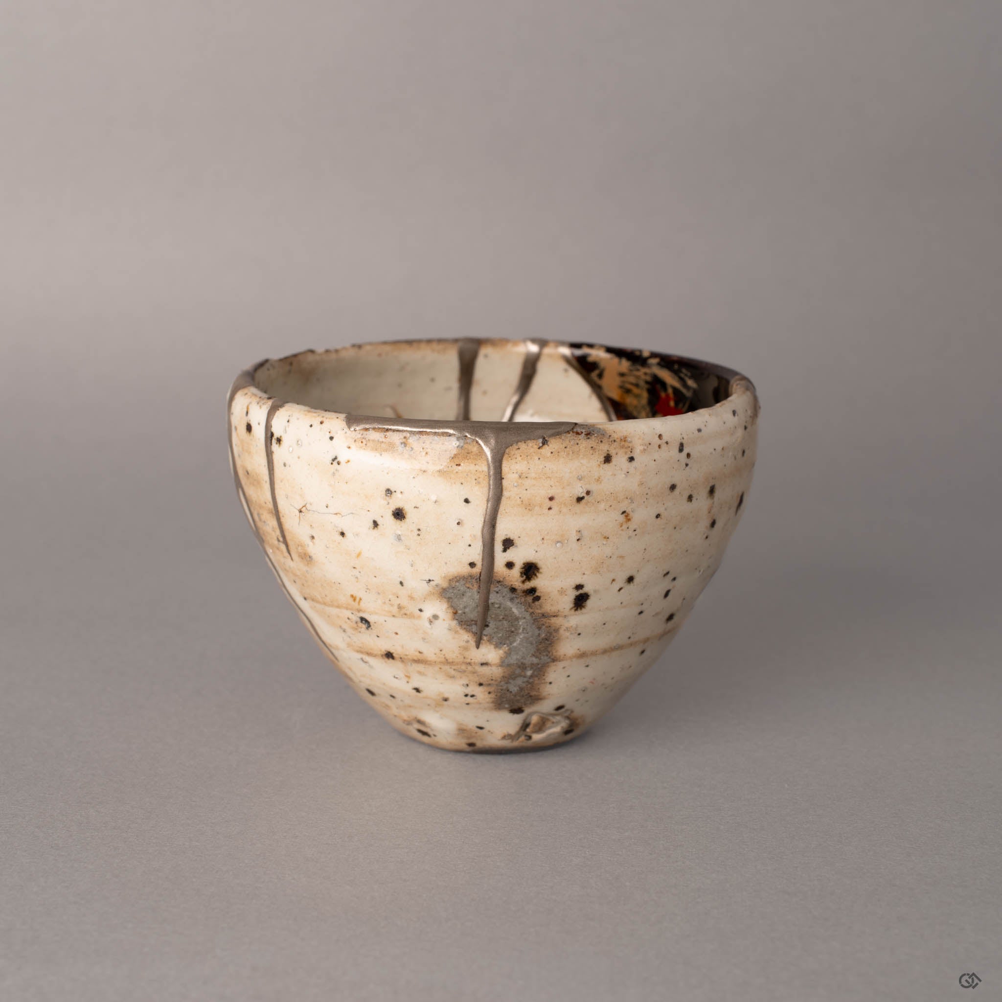 Fourth side angle of a kintsugi Shigaraki earthenware cup, silver lines marking where fragments were rejoined with natural urushi lacquer, rustic simplicity in every curve.