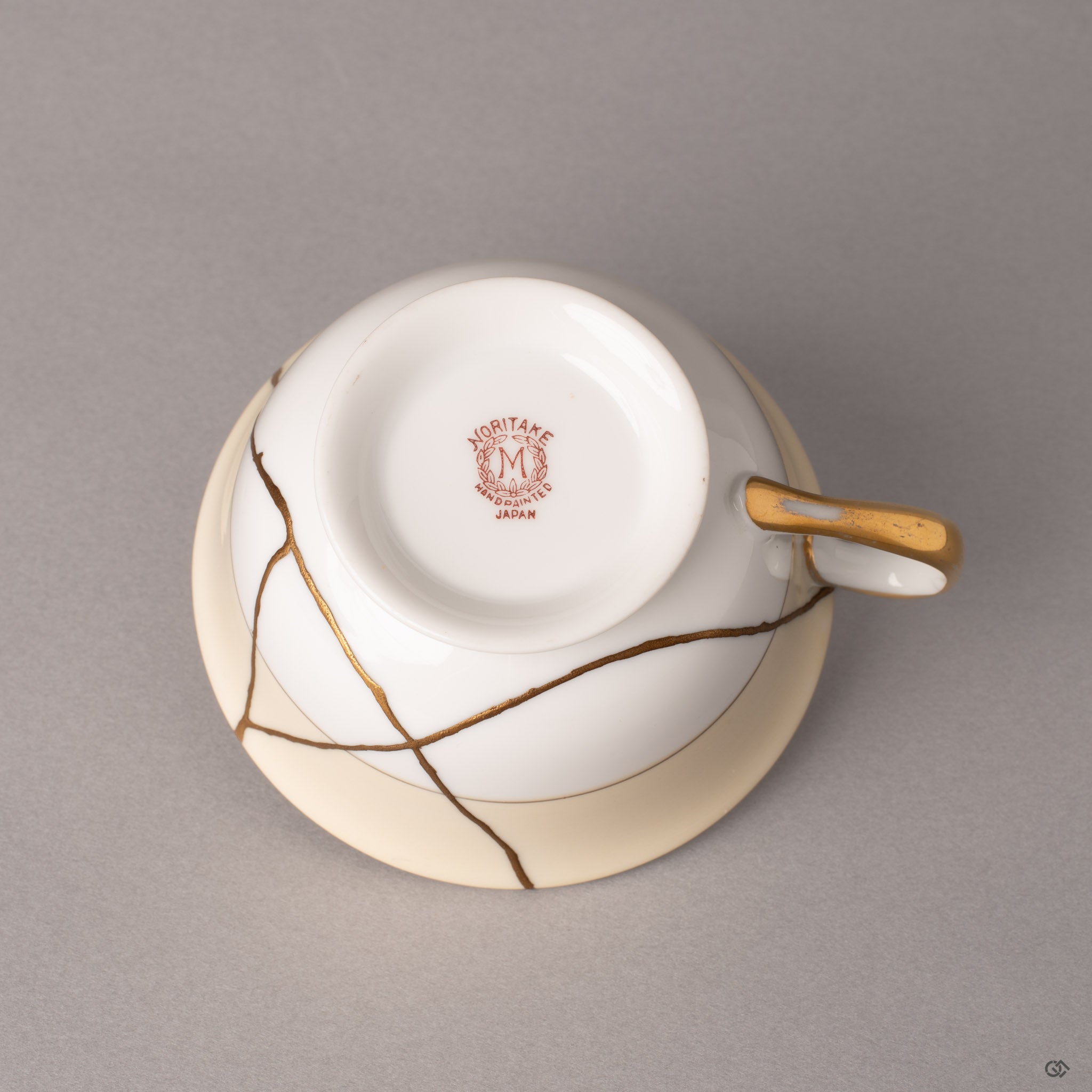 The underside of a Noritake kintsugi cup, gold seams visible even here—restoration without compromise.