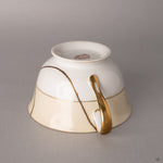 Gold kintsugi lines thread across ivory Noritake porcelain, each seam a quiet meditation on renewal.
