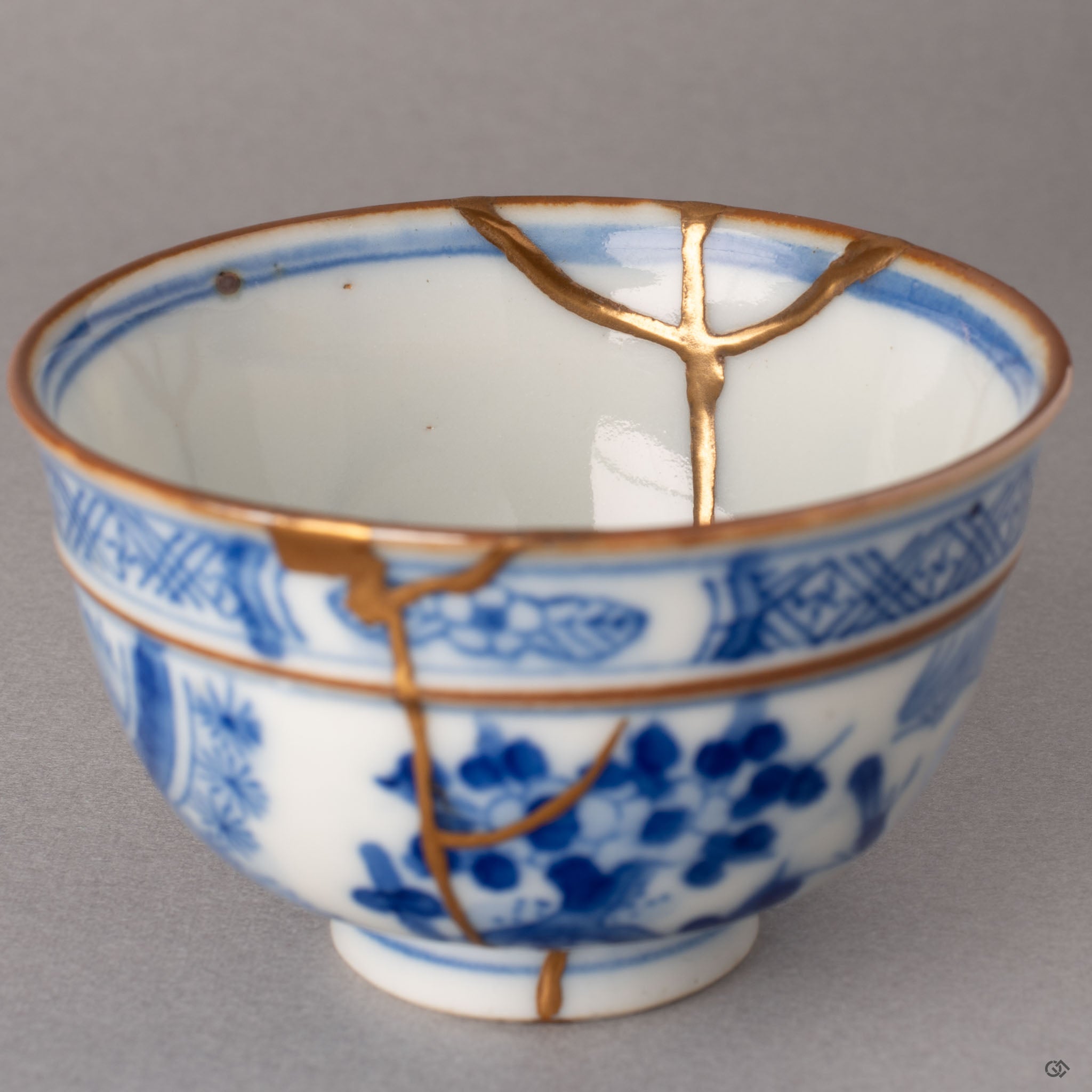 Interior of kintsugi Ko-Imari cup revealing gold-finished restoration lines across the white porcelain floor, slow craft in each seam.
