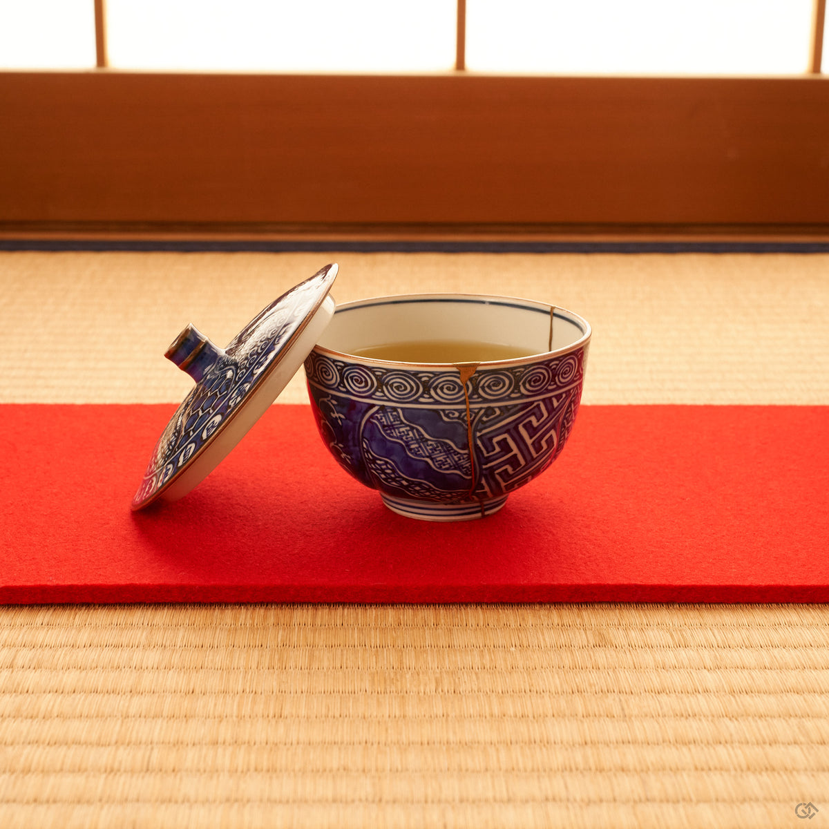 Kyoto ware kintsugi cup set on tatami, sometsuke cobalt blue porcelain with a single 24K gold seam and fitted lid, quiet tea-setting context.
