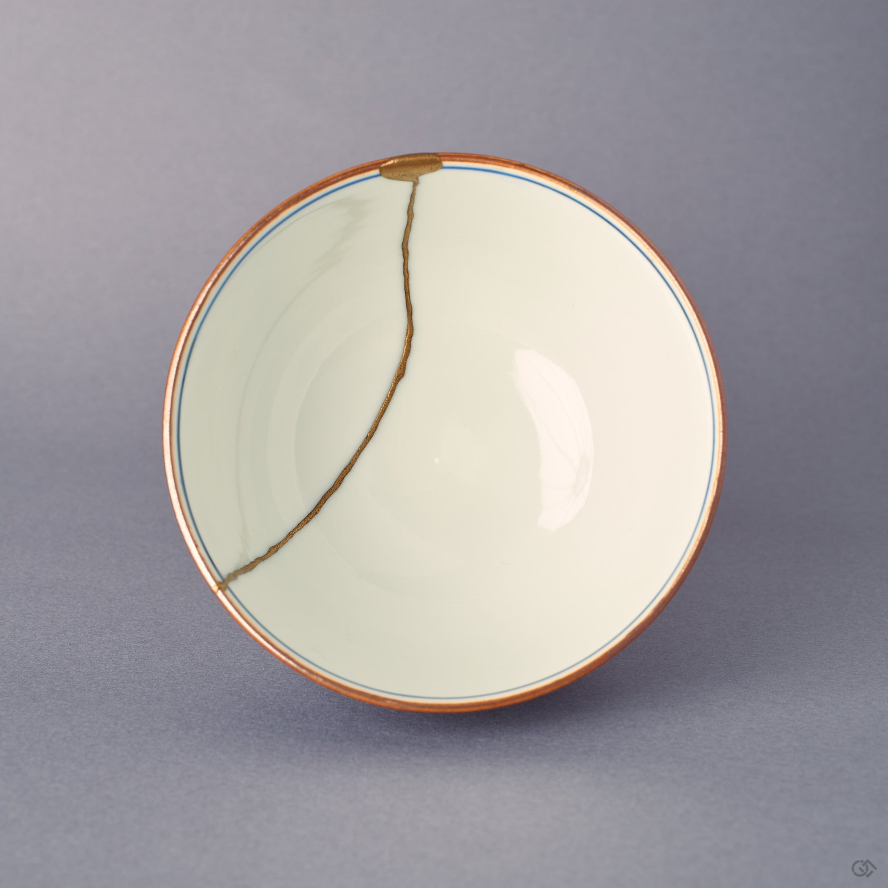 Overhead view into the Kyoto ware kintsugi cup, sometsuke blue Uzu-komon band around the rim, 24K gold seam descending the inner wall, lid removed.