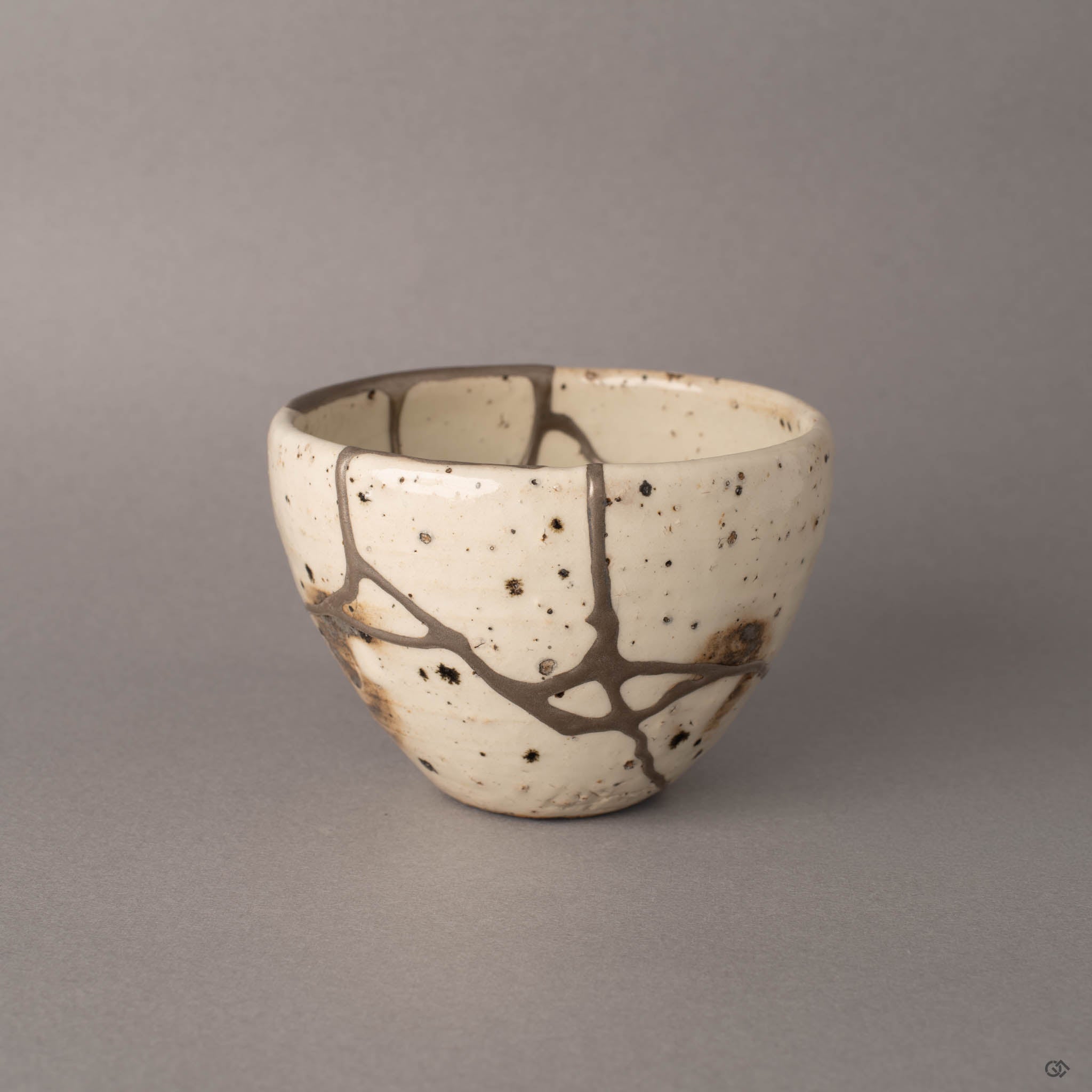 Silver kintsugi Shigaraki earthenware cup with branching seams on ivory white, front view, a philosophy in form.