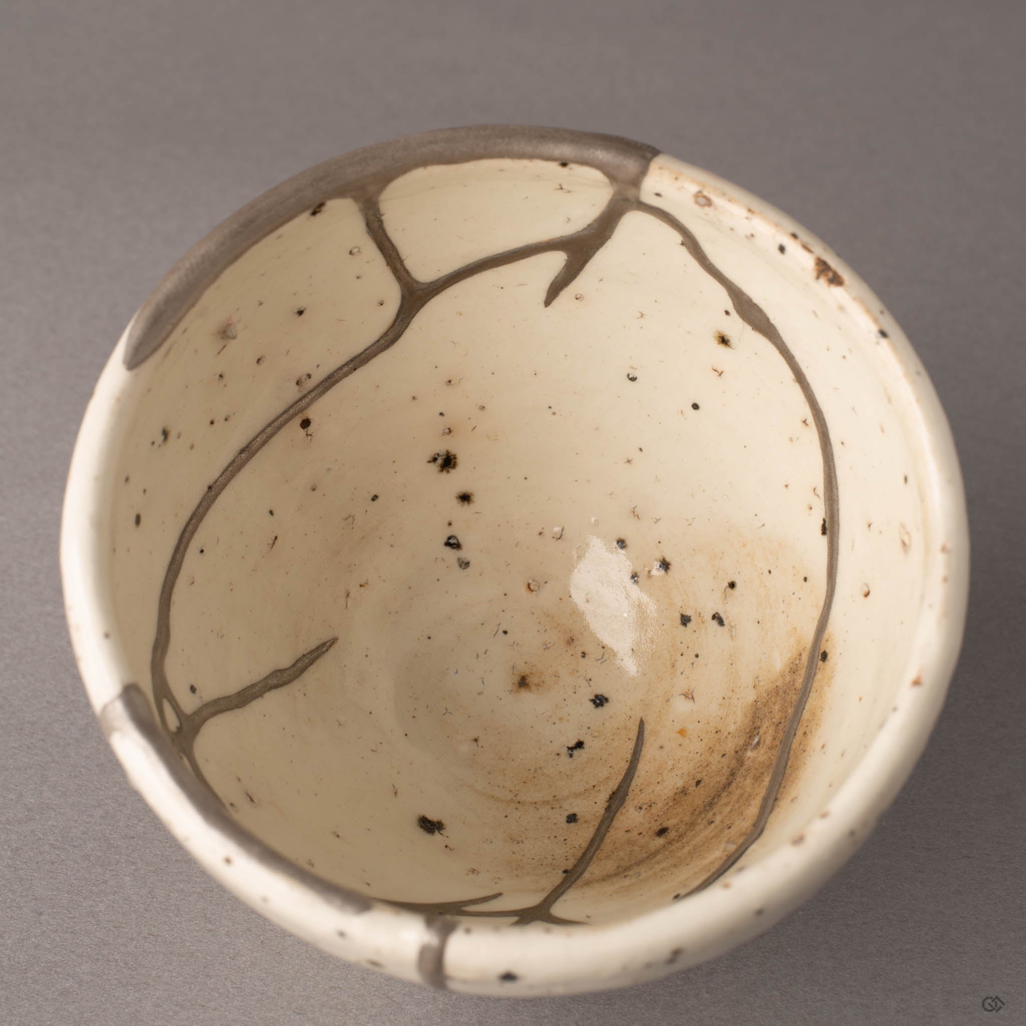 Detail of silver kintsugi restoration inside Shigaraki earthenware cup, natural clay texture and seam precision visible.