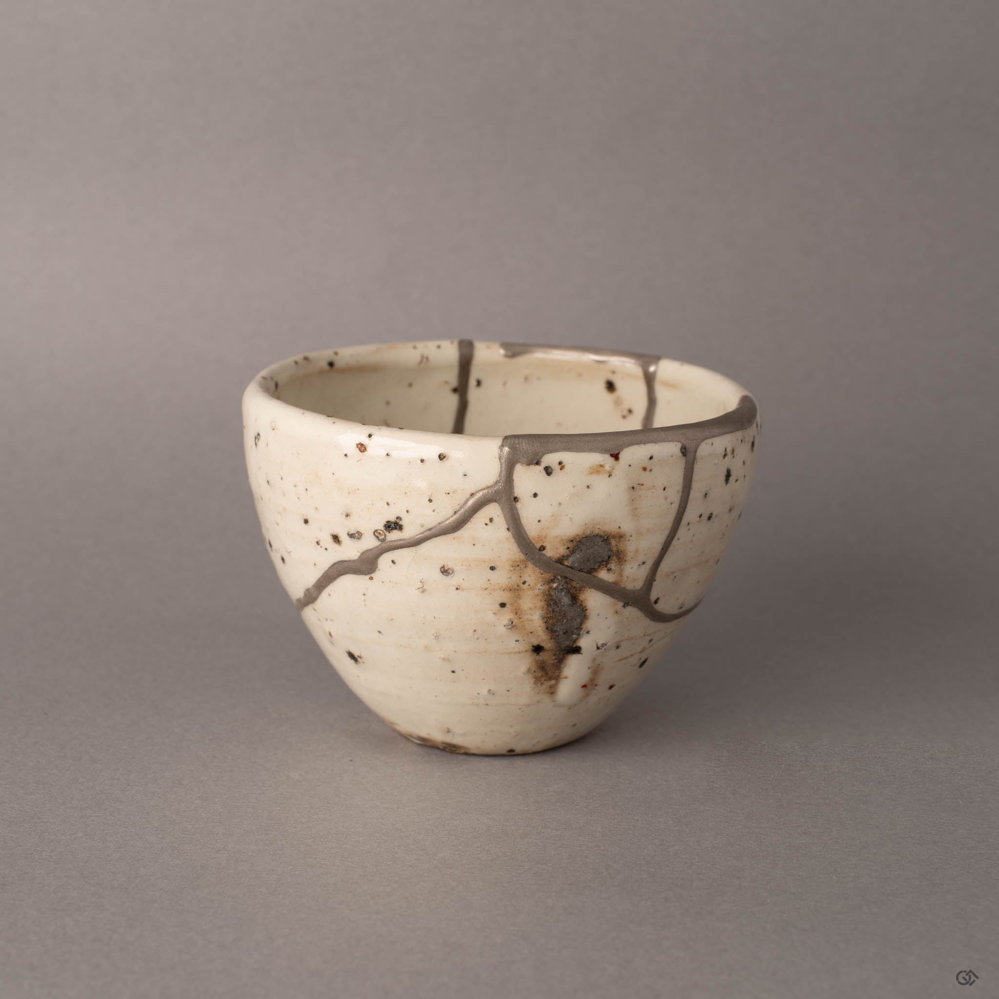 Shigaraki kintsugi cup from the side showing silver restoration lines on speckled earthenware, rustic simplicity.