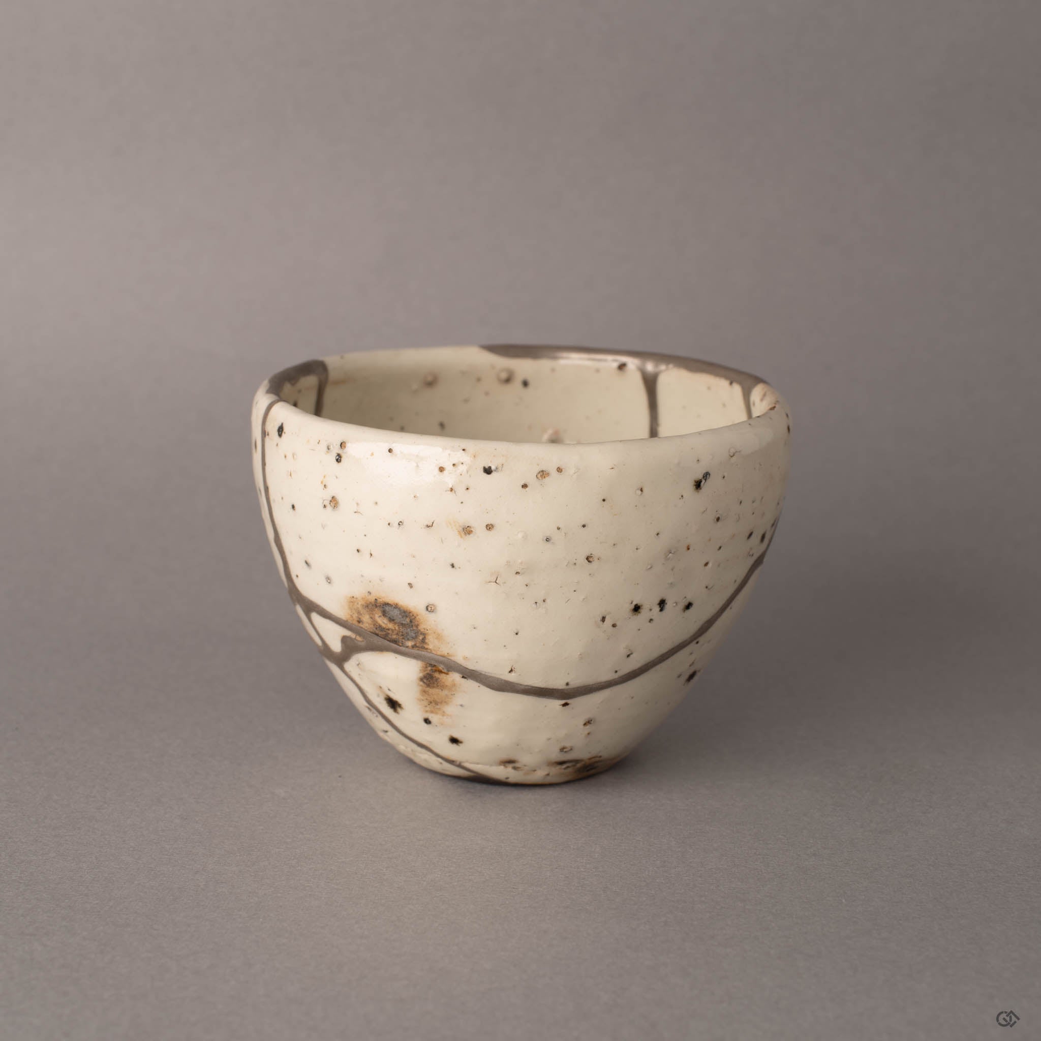 Side angle of silver kintsugi Shigaraki cup revealing natural iron spots beneath the branching seams, patina of time.