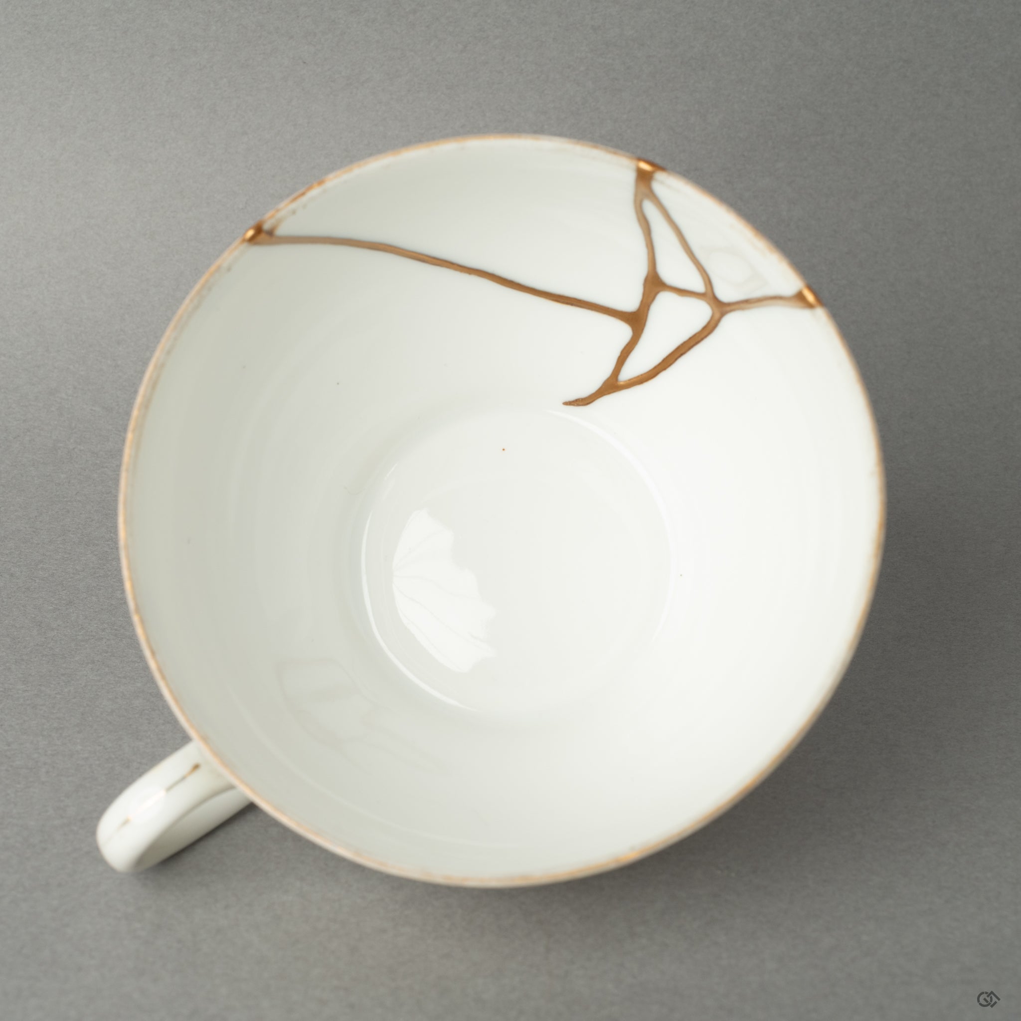 Top-down view of a restored Noritake kintsugi cup, its golden seam encircling quiet imperfection—crafted as a tangible piece of Japanese philosophy.