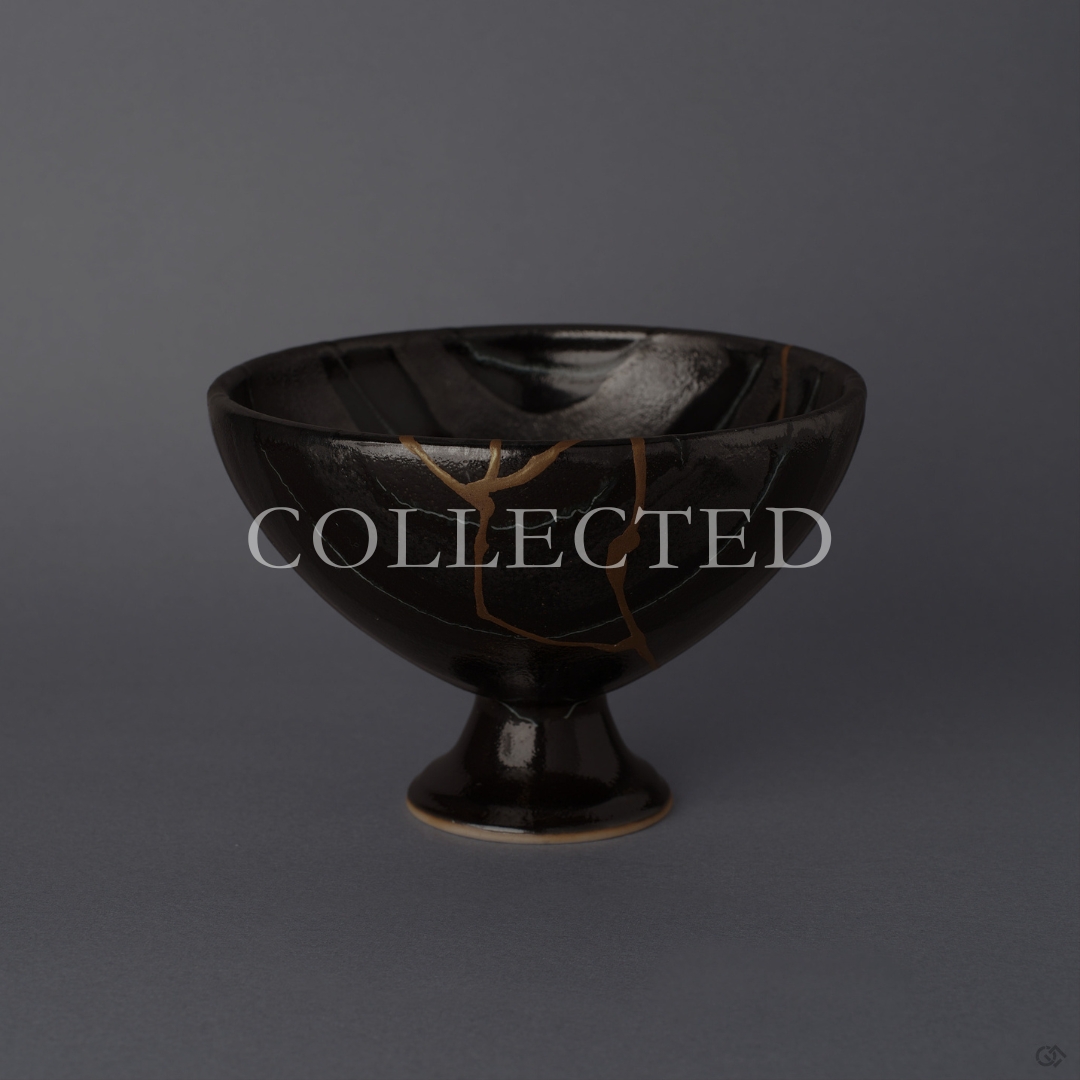 Arita ware footed bowl in glossy black porcelain with a 24K gold kintsugi seam descending the striped body, raised on a slender pedestal foot, shown from the front. Sold out.