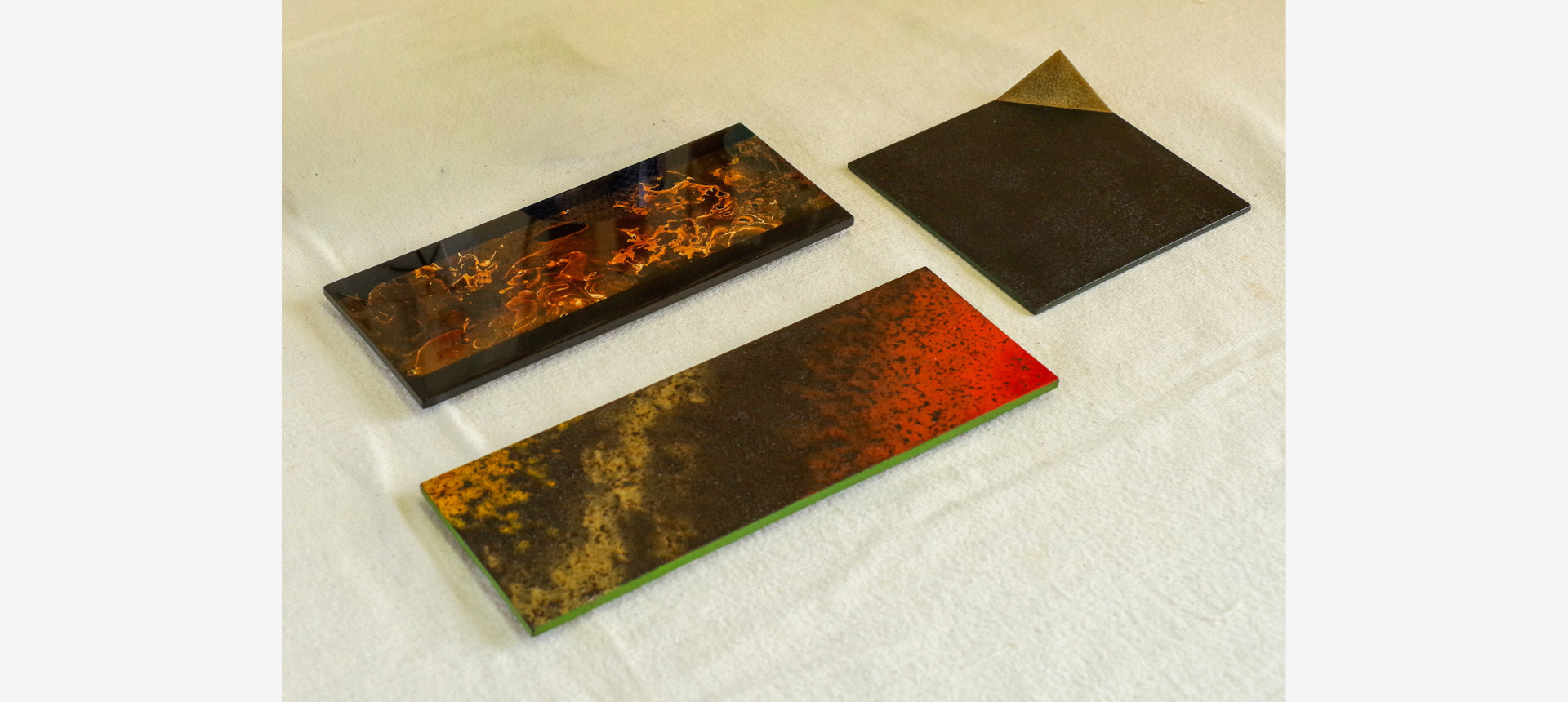 Three urushi lacquer panels showcasing various decorative techniques in the Hikone workshop of Seisaku Nakajima, a nationally certified urushi master.