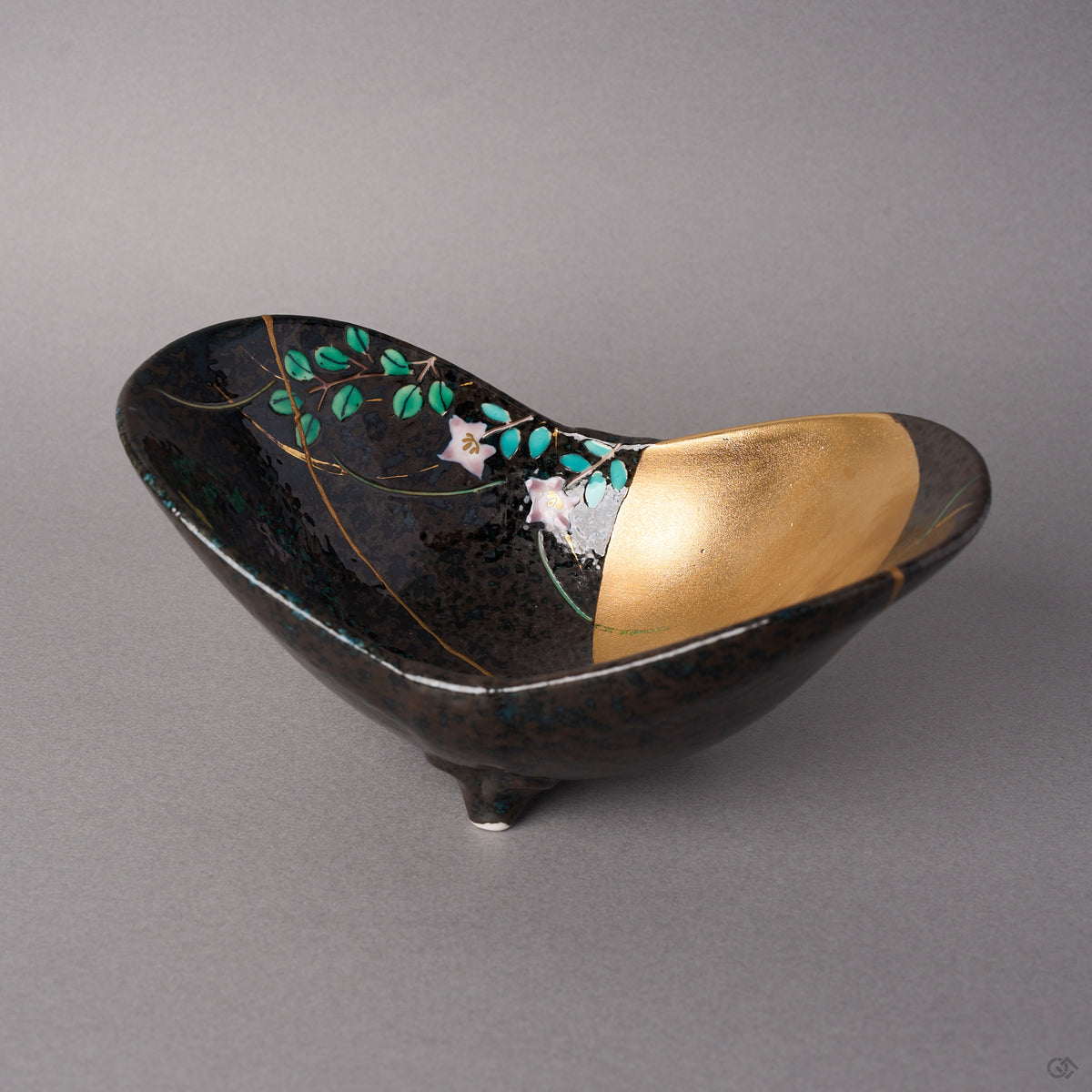 Kintsugi Arita ware bowl in black glaze with autumn grasses and a gold moon, rejoined with natural urushi, one 24K gold seam down the outer wall, front view.