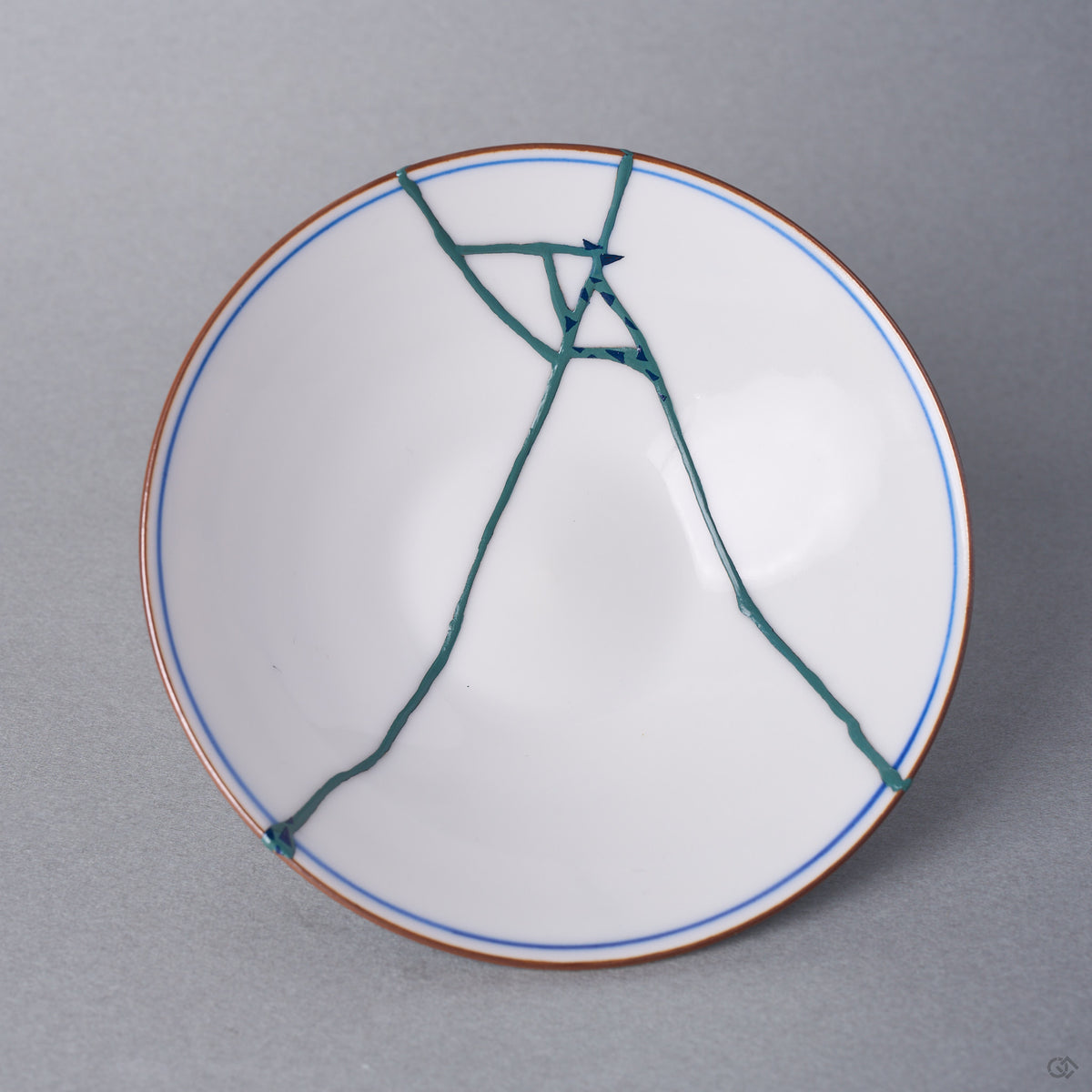 Kintsugi bowl lid interior in Arita porcelain, the fracture finished in green colored natural urushi with tiny blue triangles, opposite its 24K gold face.
