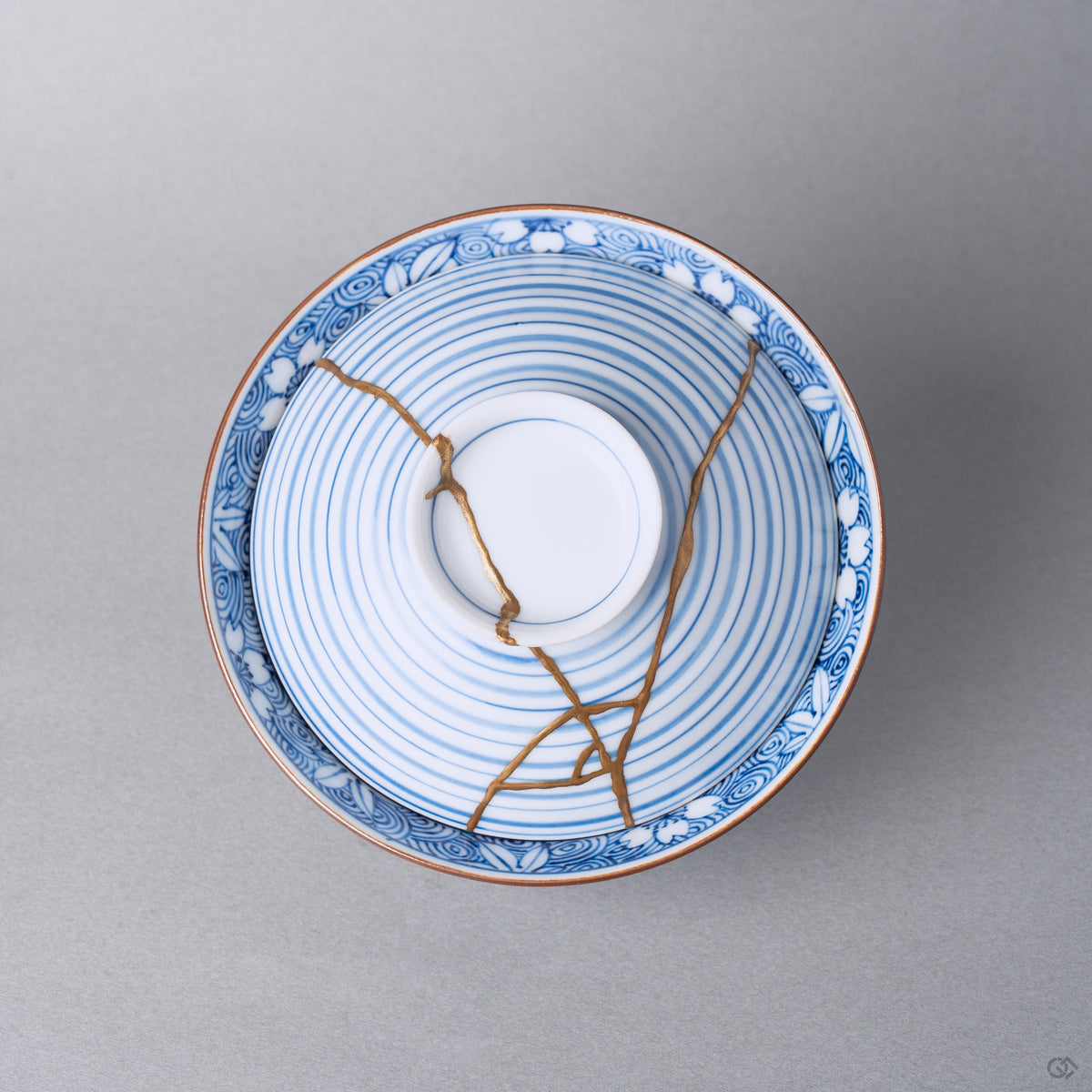 Kintsugi bowl with lid in Arita porcelain from above, natural urushi and 24K gold lines crossing the concentric blue rings of the lid inside the wave band.