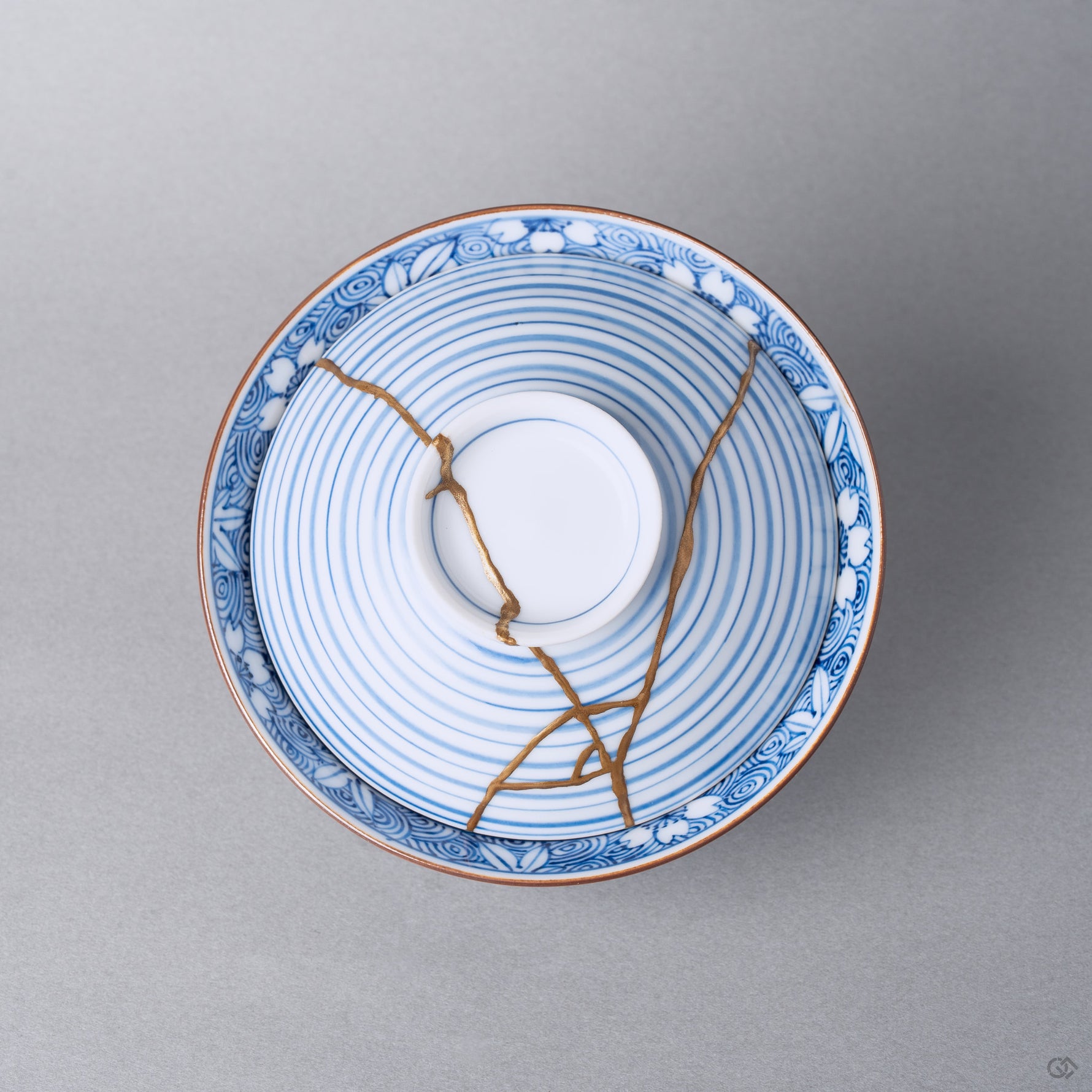 Kintsugi bowl with lid in Arita porcelain from above, natural urushi and 24K gold lines crossing the concentric blue rings of the lid inside the wave band.