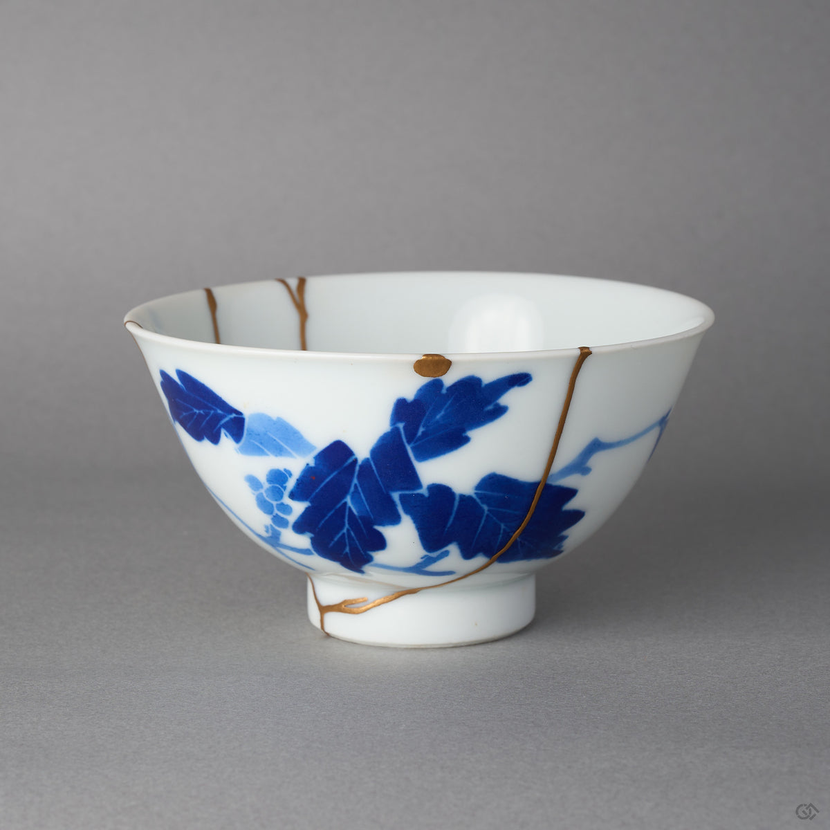 Kintsugi bowl in Ko-Imari porcelain with grape leaves, rejoined with natural urushi, one 24K gold seam from the foot to the rim, front view.