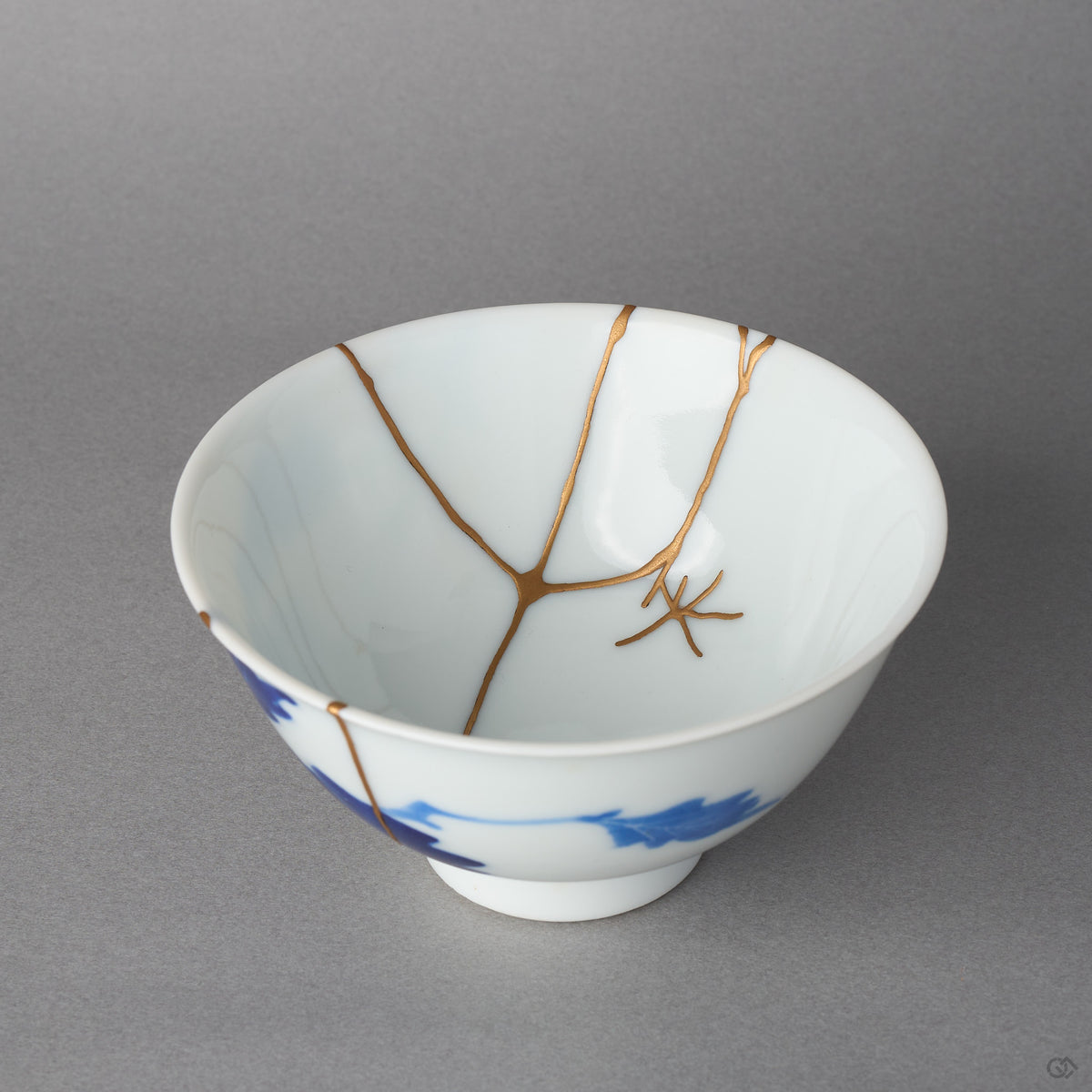 Kintsugi bowl in Ko-Imari porcelain, rejoined with natural urushi, 24K gold lines meeting near the center with fine branches, interior close-up.