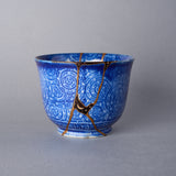 Ko-Imari cup with authentic kintsugi repair seams finished in 24K gold, cobalt spirals, and moon-and-star urushi decoration.