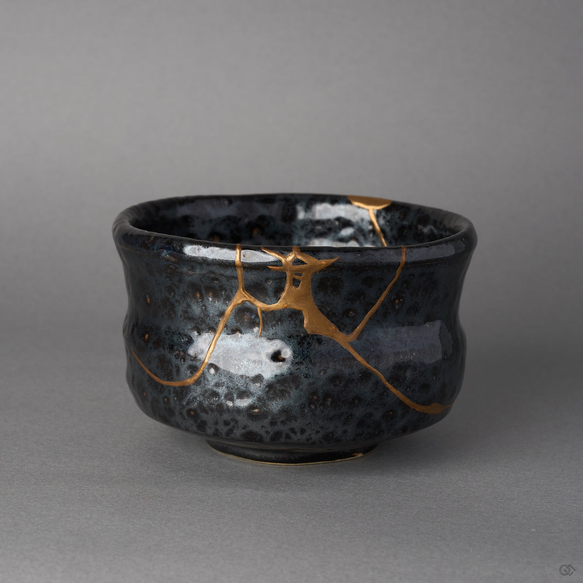 Kintsugi matcha bowl, oil-spot black Arita ware, rejoined with natural urushi, branching 24K gold seam at the rim, front view.