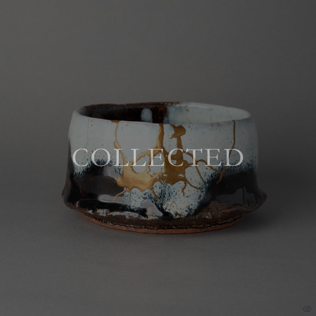 Kintsugi matcha bowl in Karatsu stoneware, white glaze over black, rejoined with natural urushi, a 24K gold field and root-like seams. Collected.