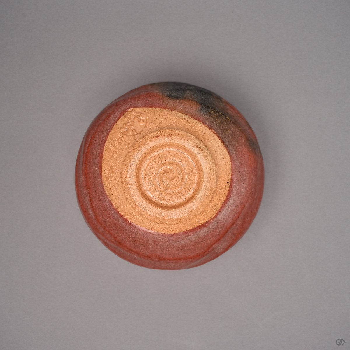 Kintsugi matcha bowl in Raku-style Kyoto ware turned over, buff unglazed foot with a coiled spiral and a seal, natural urushi and 24K gold seams above.