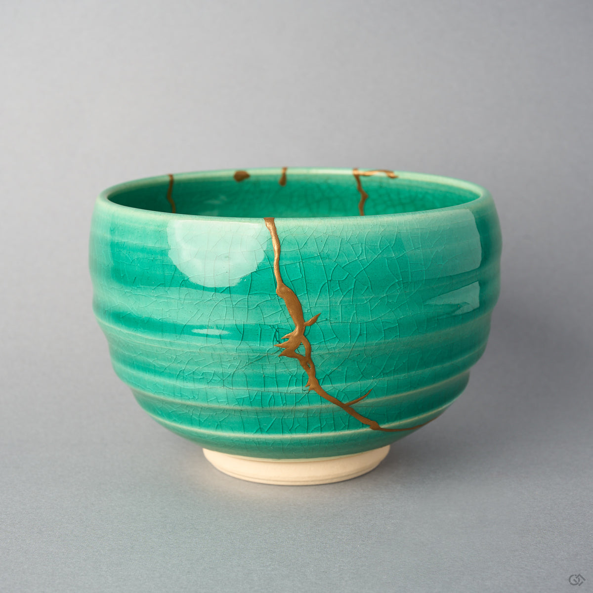 Kintsugi matcha bowl in Kyoto ware: a branching seam of natural urushi and 24K gold descends the emerald crackle glaze from the rim, front view.