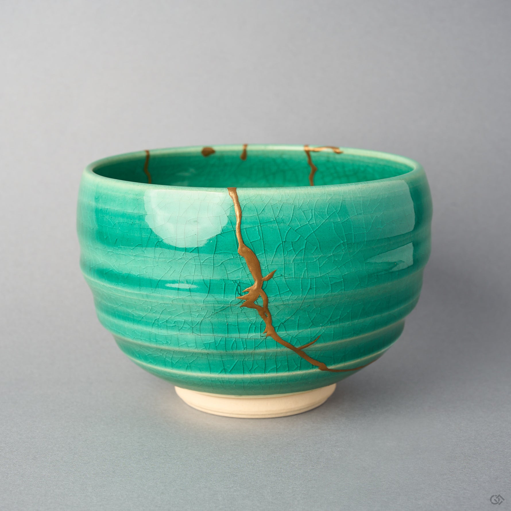 Kintsugi matcha bowl in Kyoto ware: a branching seam of natural urushi and 24K gold descends the emerald crackle glaze from the rim, front view.