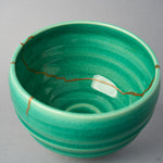 Kintsugi matcha bowl interior crossed side to side by one urushi and 24K gold seam over the emerald crackle glaze.