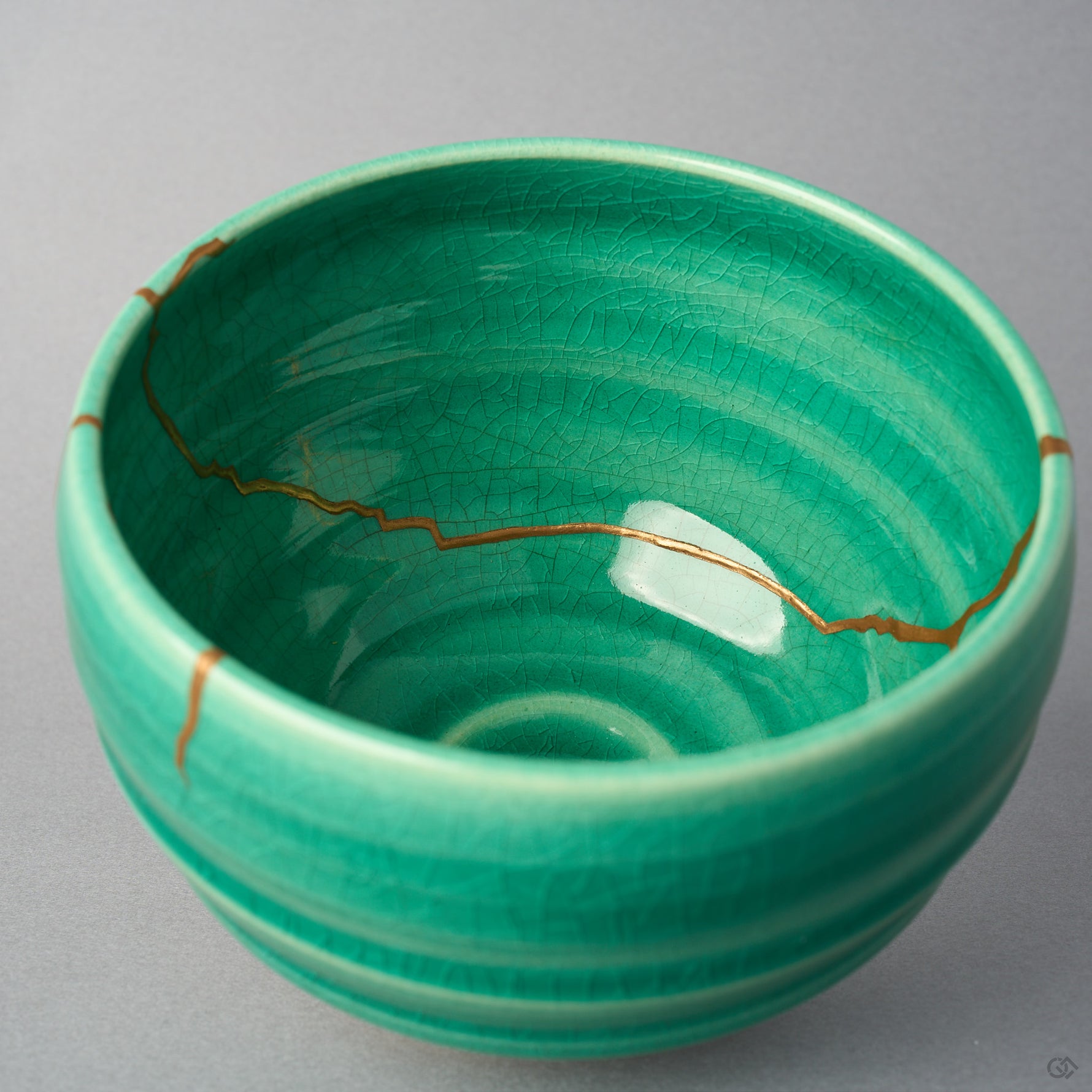 Kintsugi matcha bowl interior crossed side to side by one urushi and 24K gold seam over the emerald crackle glaze.