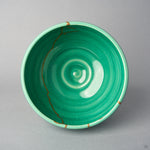 Kintsugi matcha bowl seen from above; an urushi and 24K gold line runs down the emerald crackle interior toward the center.