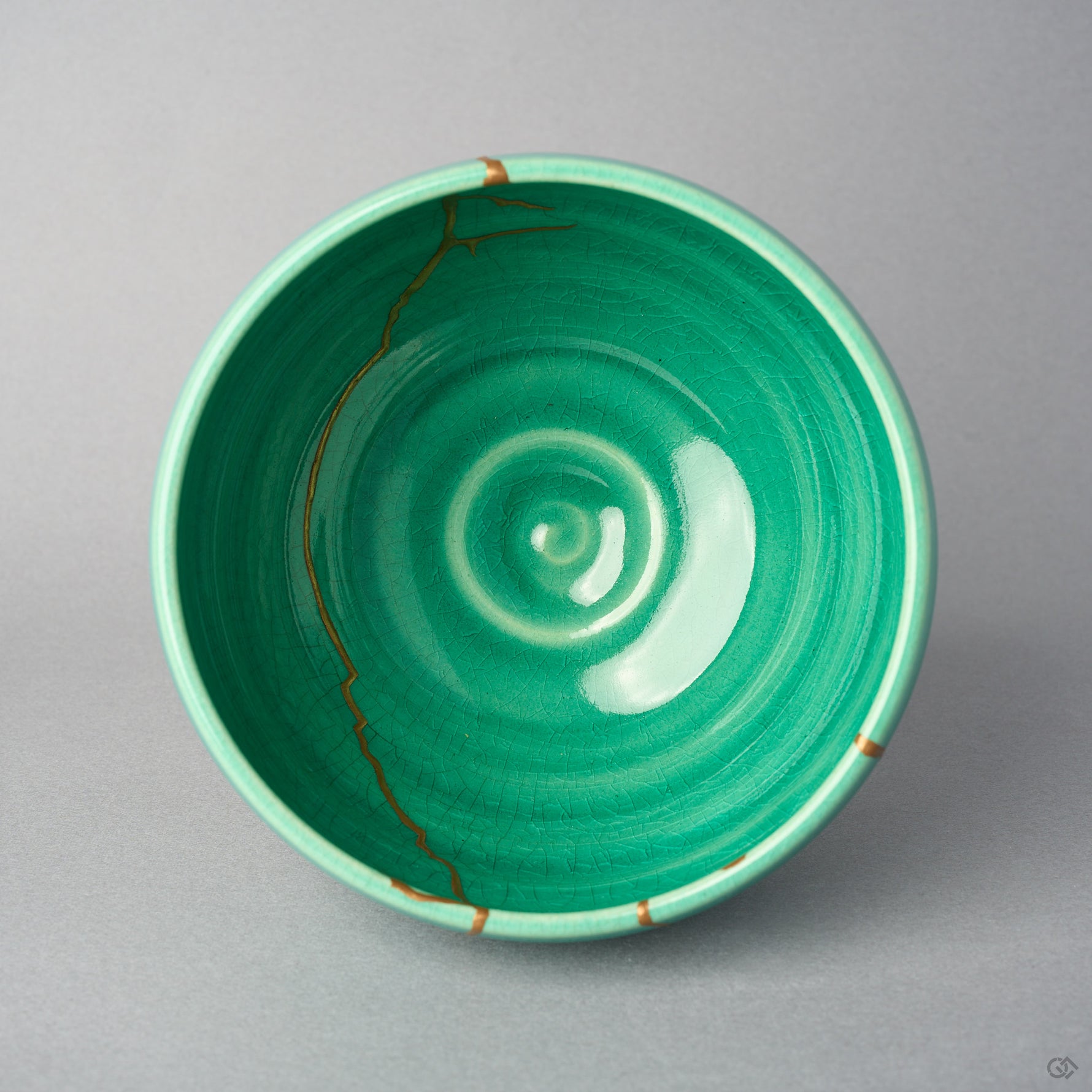 Kintsugi matcha bowl seen from above; an urushi and 24K gold line runs down the emerald crackle interior toward the center.