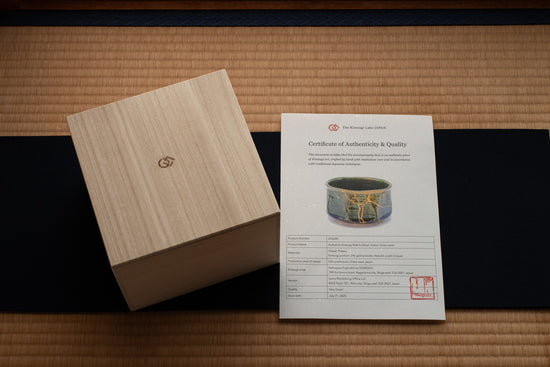 A paulownia gift box and authenticity certificate arranged on red felt over tatami, showcasing the refined presentation of each Kintsugi piece.