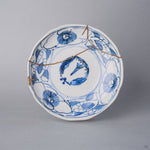 Kintsugi plate in Ko-Imari sometsuke porcelain with line-drawn camellias, a natural urushi and 24K gold seam passing through the central roundel, front view.