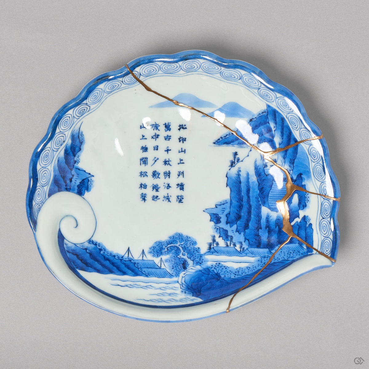 Kintsugi plate in abalone-shaped Ko-Imari porcelain, rejoined with natural urushi, one 24K gold seam crossing the sometsuke mountains to the rim, front view.
