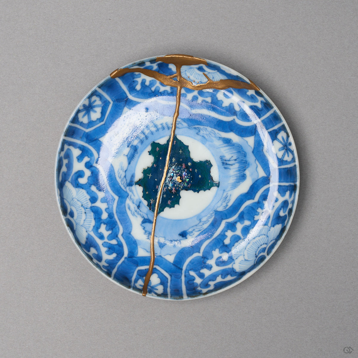 Kintsugi plate in Ko-Imari sometsuke porcelain, rejoined with natural urushi, one 24K gold seam falling from the rim across the painted night sky, front view.