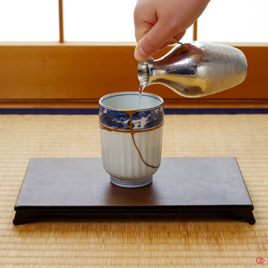 A photo of an authentic Kintsugi pottery piece being used in a real-world setting, such as a cup of sake being poured into a Kintsugi cup.