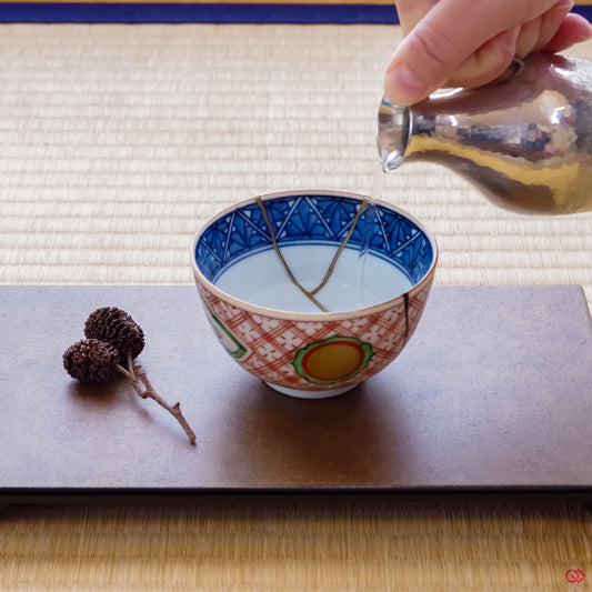 Photo of an authentic Kintsugi pottery piece being used in a real-world setting, such as a cup of sake being poured into a Kintsugi cup