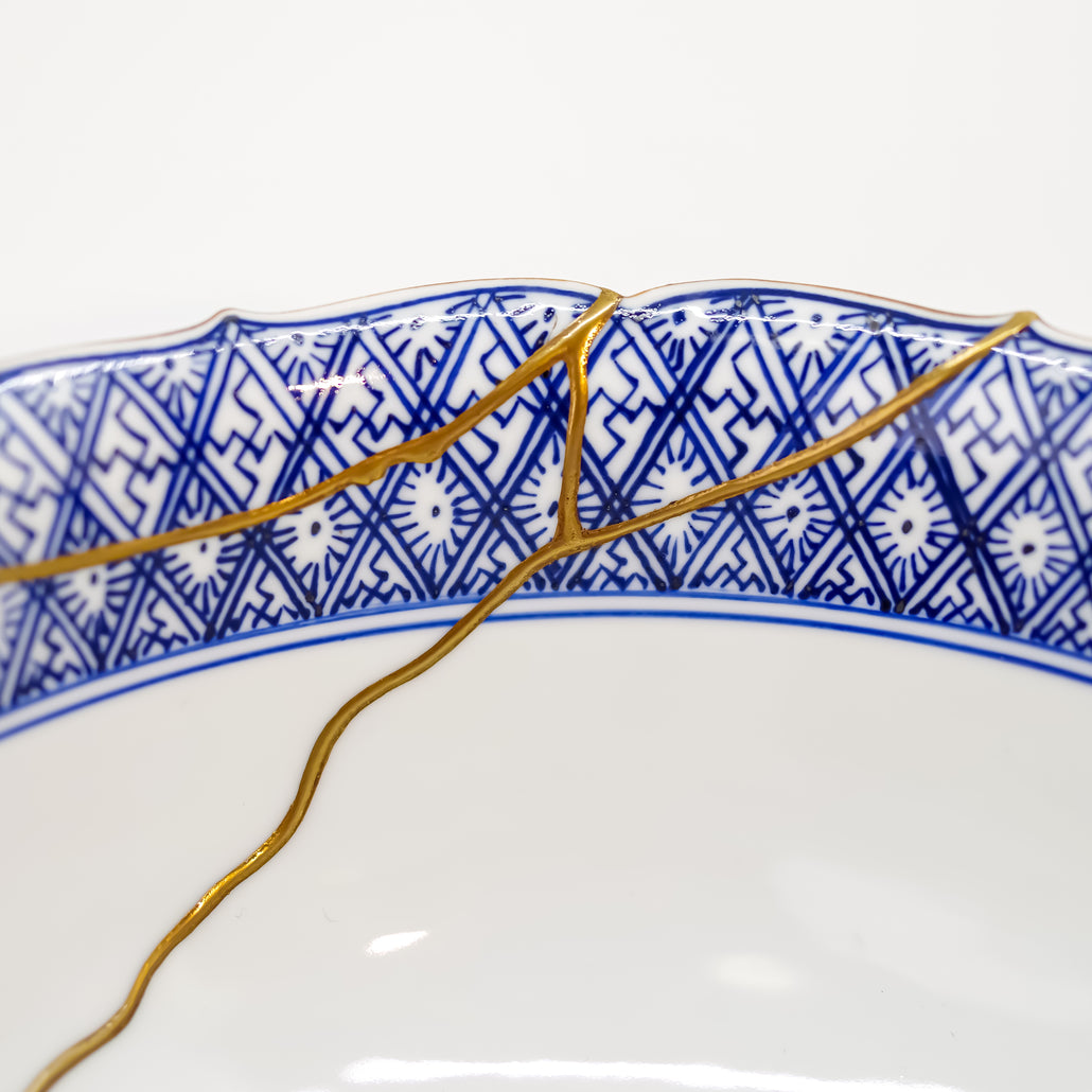 Detailed close-up of authentic Kintsugi pottery, showcasing the delicate gold lines of the repair and the artisan's craftsmanship.