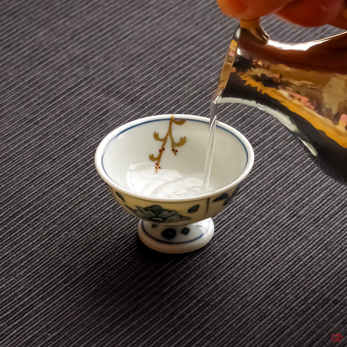 Photo of an authentic Kintsugi pottery piece being used in a real-world setting, such as a cup of sake being poured into a Kintsugi cup
