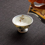 Photo of an authentic Kintsugi pottery piece being used in a real-world setting, such as a cup of sake being poured into a Kintsugi cup