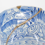 A close-up photo of an authentic Kintsugi pottery piece, showing the detail of its repairs and craftsmanship.