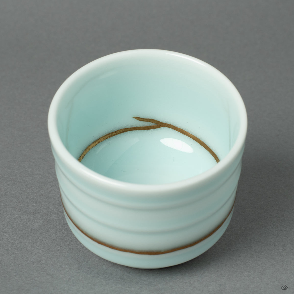 A detailed macro view of a 24k gold Kintsugi seam on the Arita ware porcelain. This close-up reveals the meticulous application of urushi lacquer and rich gold powder.